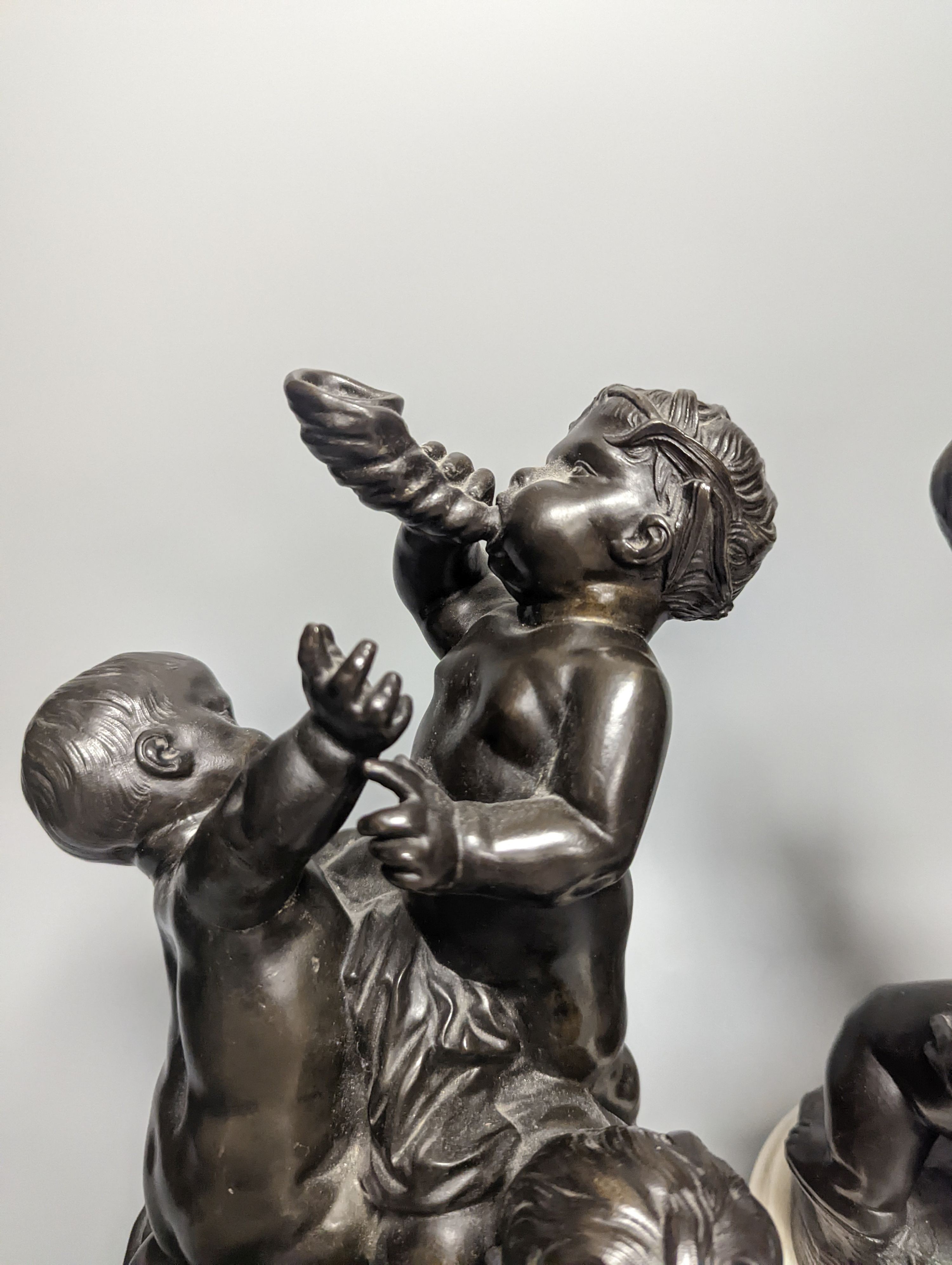 A pair of bronze figure groups, trio of putto, on white marble plinths, tallest 26cm